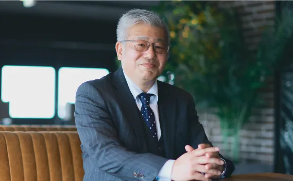 座りながら手を組みこちらを見る男性