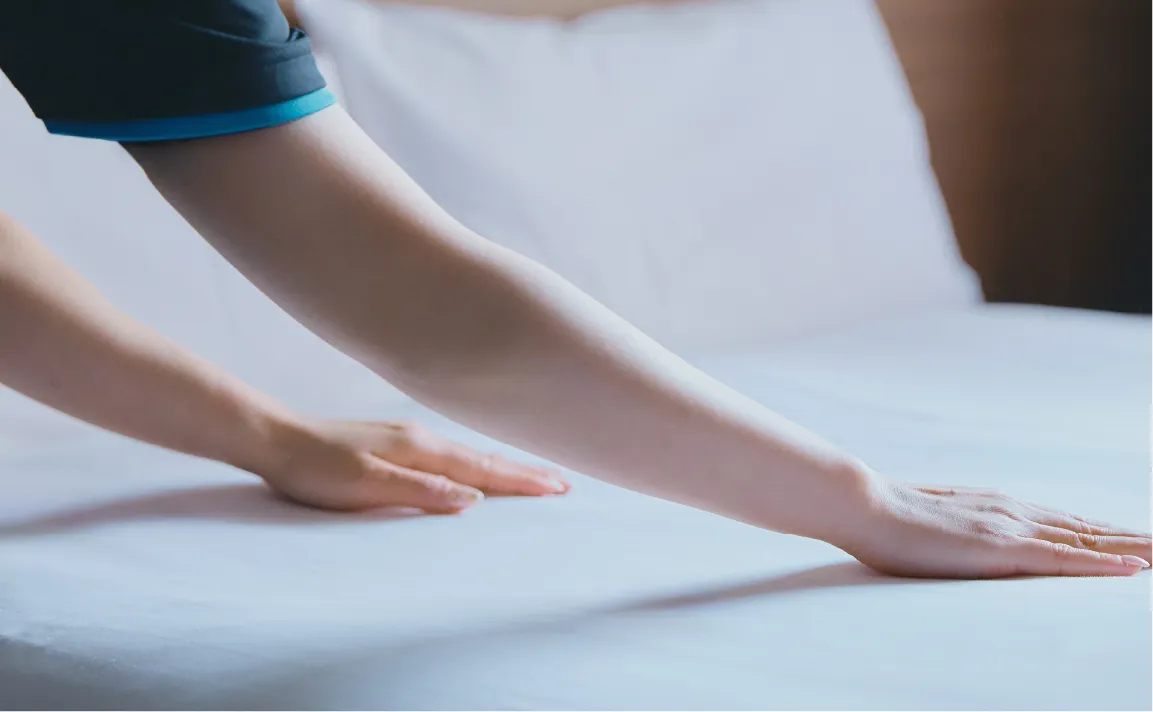 ベッドを整える女性の手