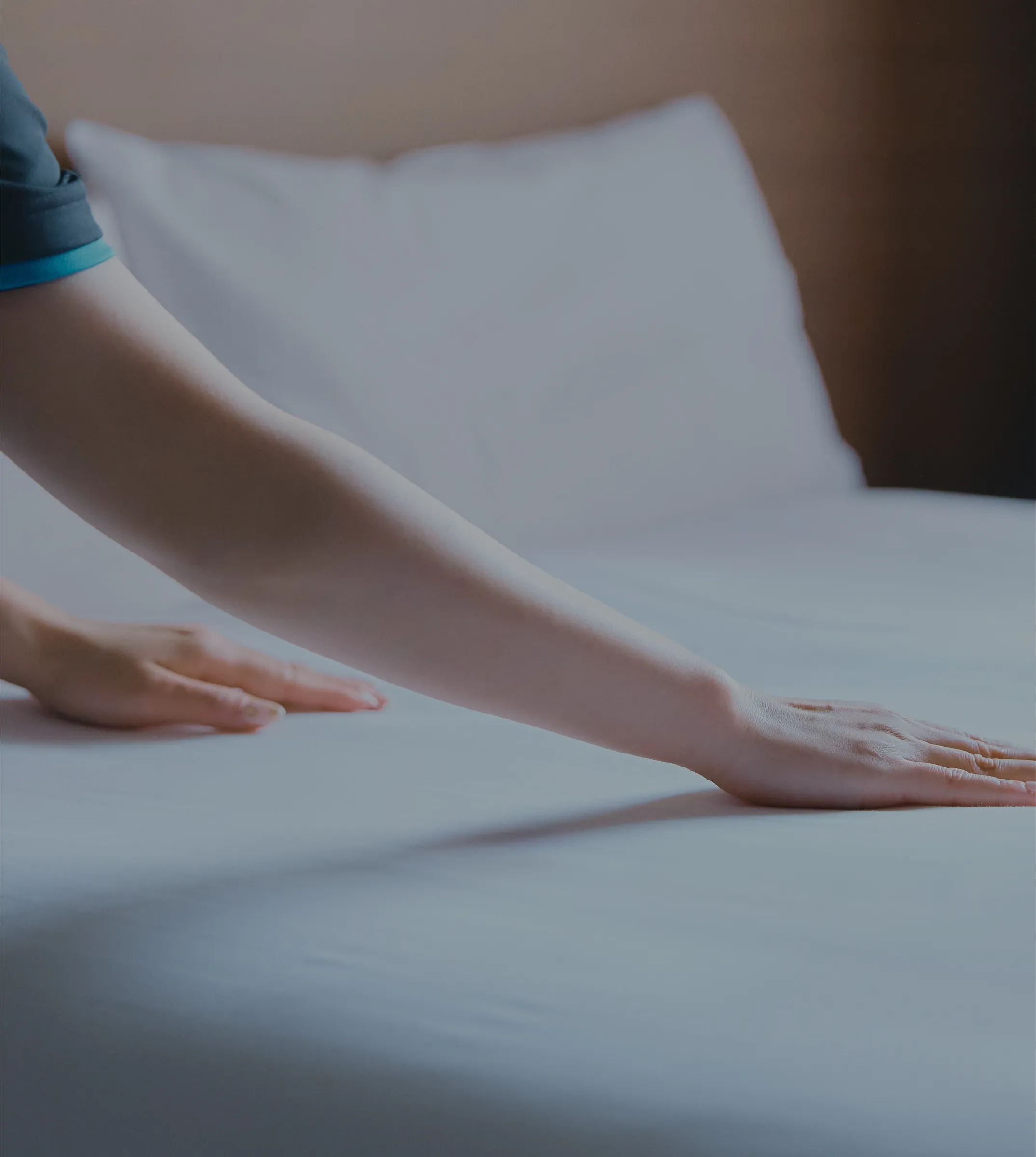 ベッドメイキングをする人の手